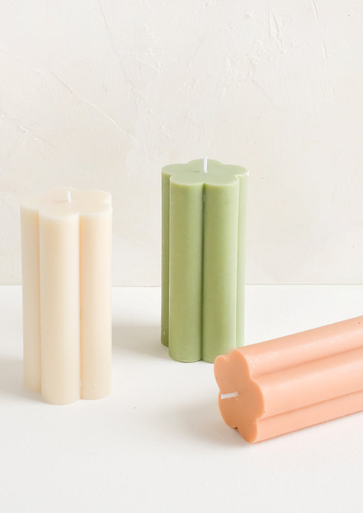 Three flower shaped pillar candles in assorted colors.