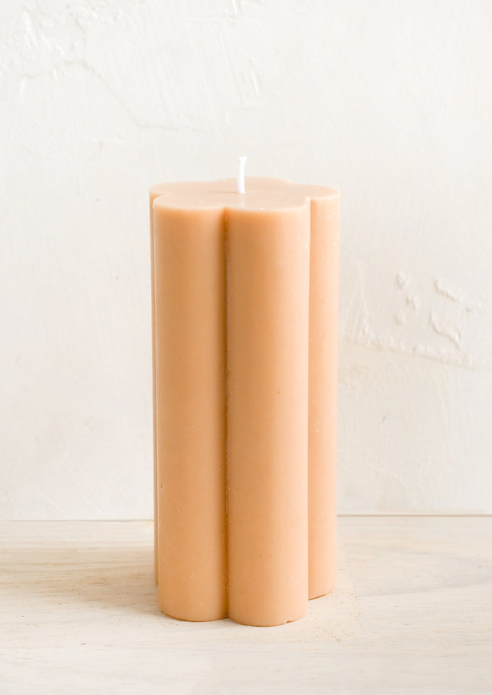 A flower shaped pillar candle in nude peach color.
