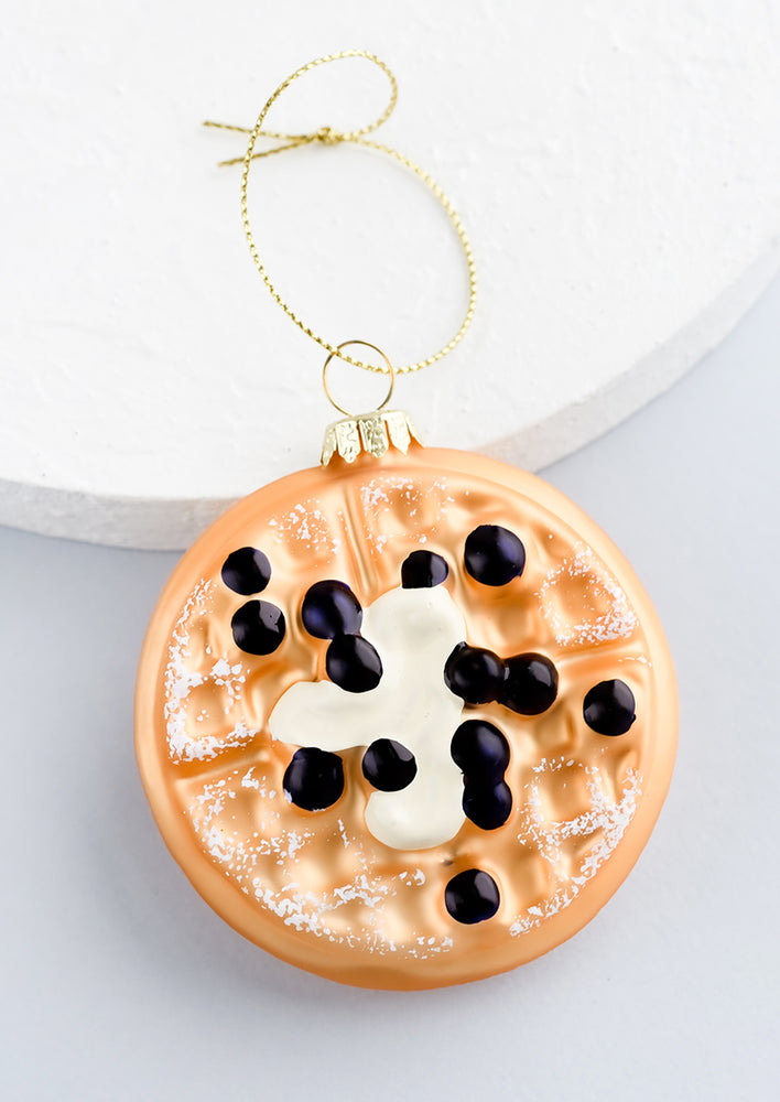 A decorative glass ornament in shape of waffle with blueberries.