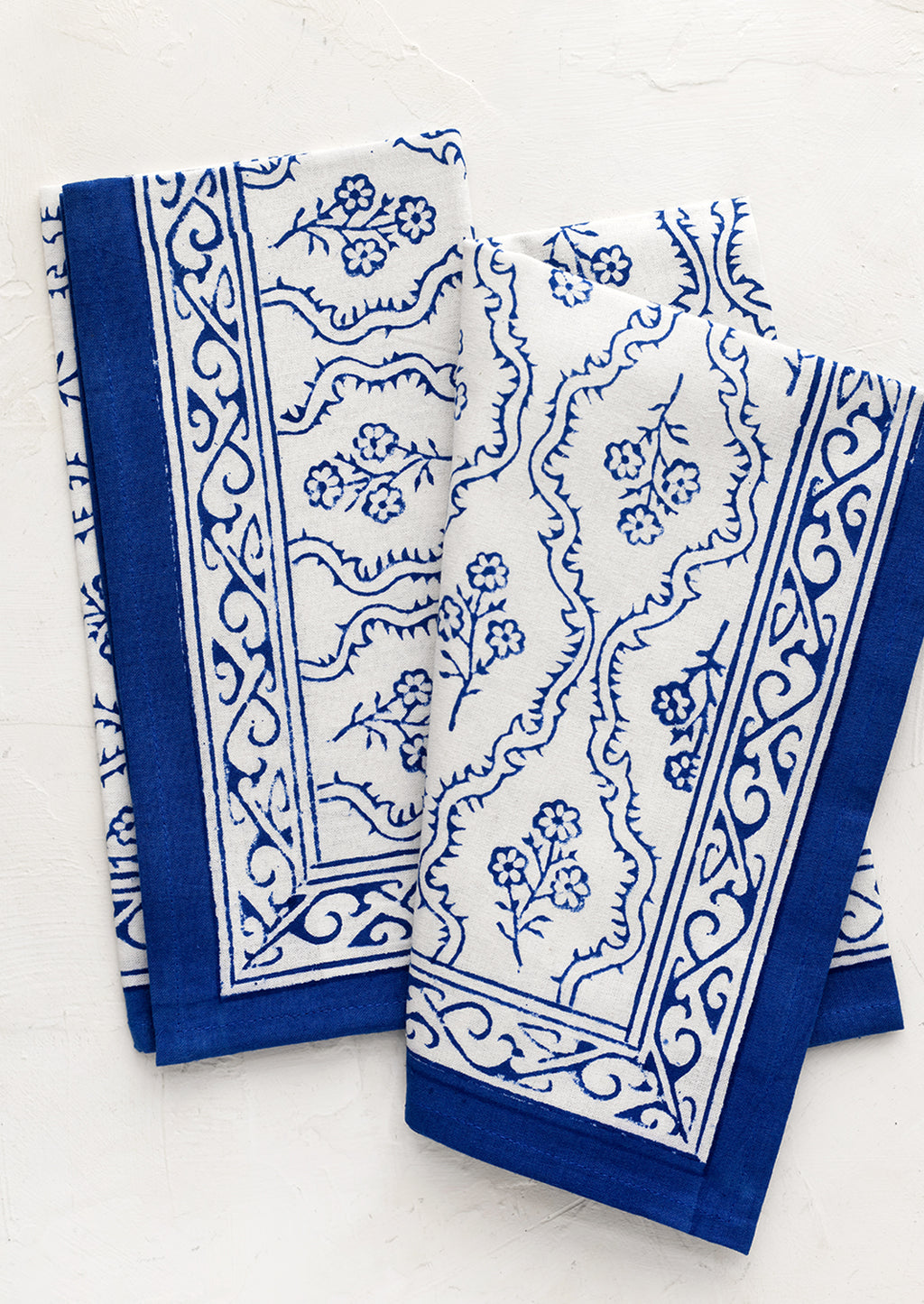 1: A pair of blue and white floral block print napkins.