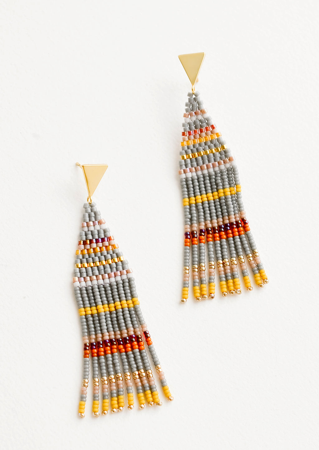 Pewter Multi: Fringe beaded earrings in gray with yellow, orange, gold, and maroon horizontal stripes on a triangular gold post.