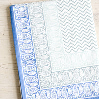1: Chevron patterned tablecloth with paisley border in shades of blue, folded on a table