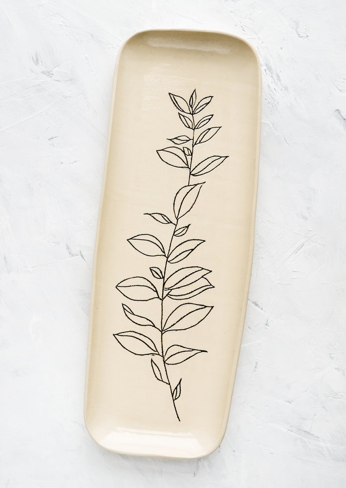 A long and skinny ceramic tray in natural bisque color with an etched black drawing of a Bay Laurel plant.