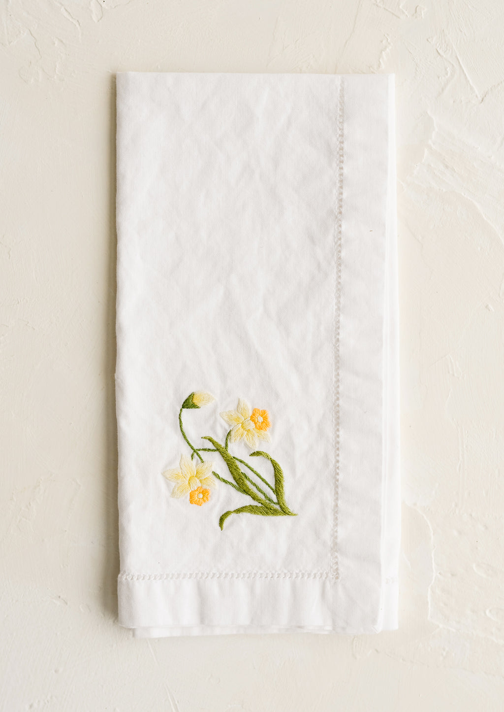 Daffodil: A white cotton napkin with daffodil embroidery.