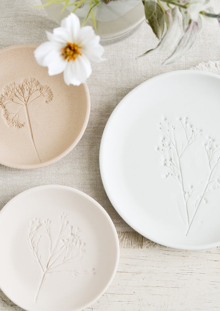 3: Stacked pastel porcelain plates with plant imprint designs.