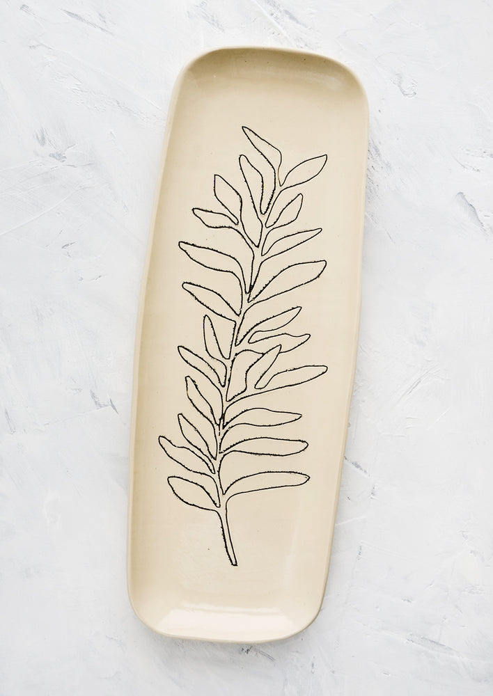 A long and skinny ceramic tray in natural bisque color with an etched black drawing of a Sage plant.