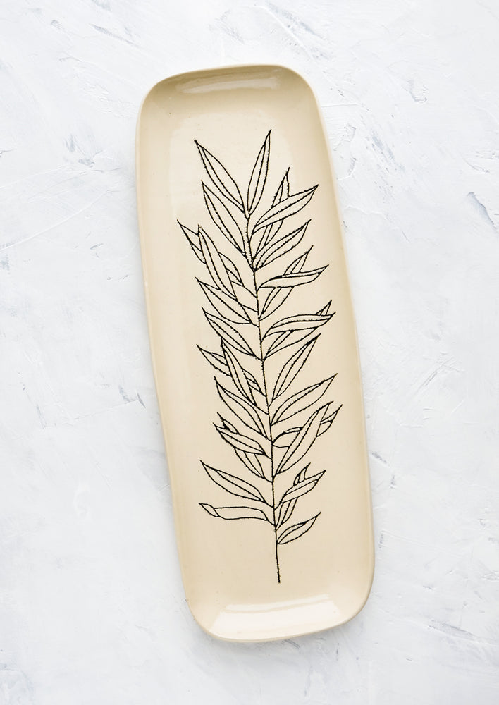 A long and skinny ceramic tray in natural bisque color with an etched black drawing of a Willow plant.