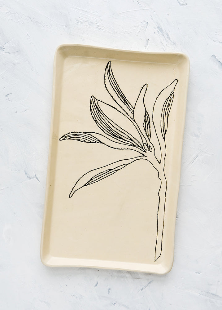 A rectangular ceramic tray in natural bisque color with an etched black drawing of a Magnolia branch.