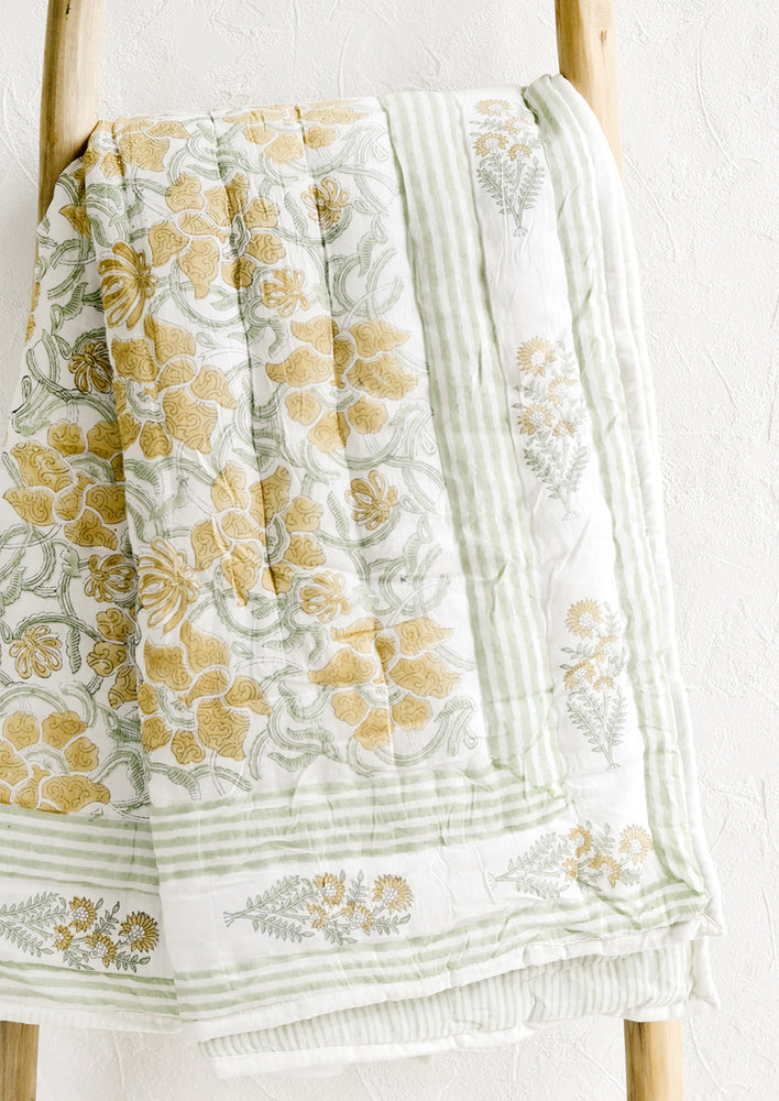 1: A padded quilt with block printed botanical print in green and yellow.