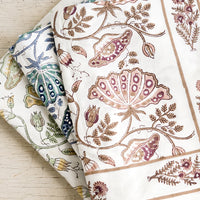 3: A stack of botanical block printed tablecloths in three colors.