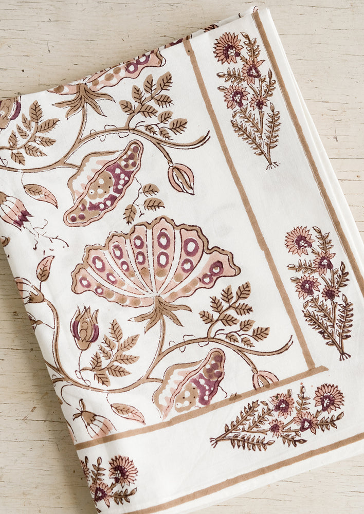 A botanical block printed tablecloth in brown, pink and wine.