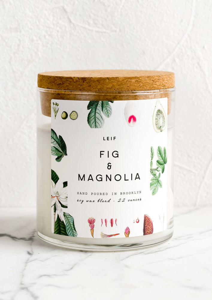A glass jar candle in Fig & Magnolia scent with botanical print label.