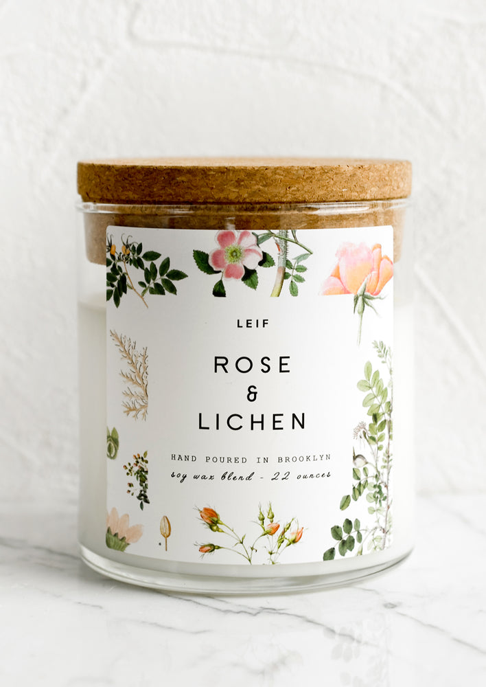 A glass jar candle in Rose & Lichen scent with botanical print label.
