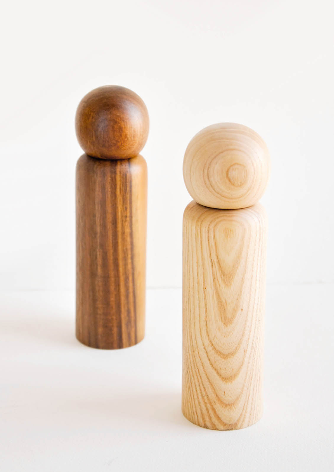 Two minimal Wooden Salt & Pepper Grinders with Spherical Tops in dark and light wood.