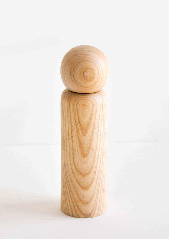 Minimal salt grinder in a light wood showing a curvy grain pattern.