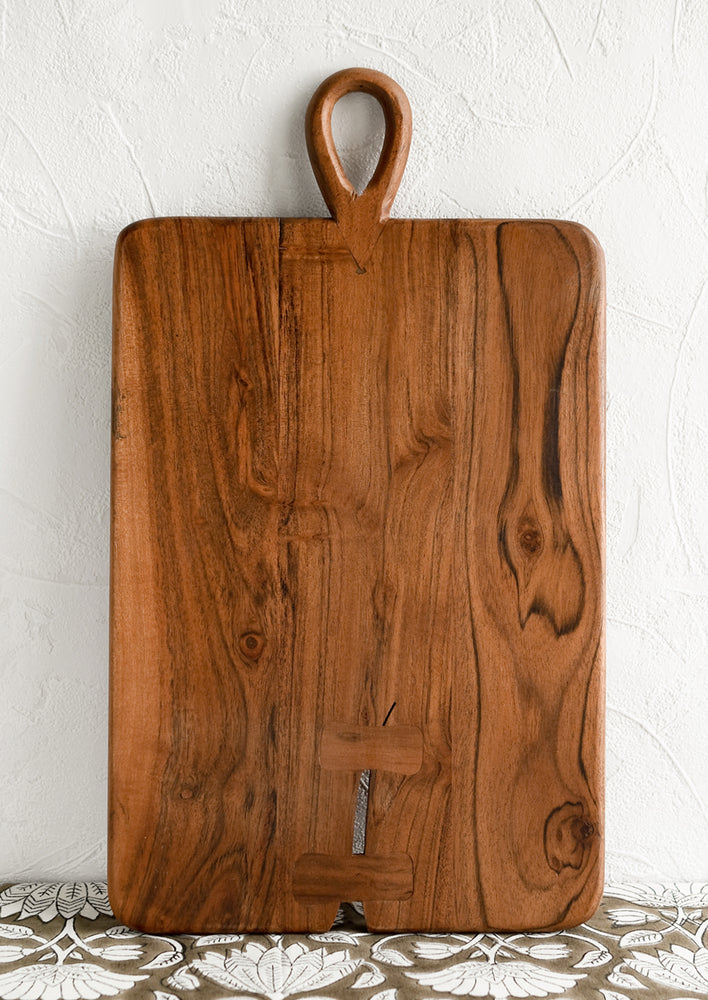 1: A rectangular cutting board with loop handle at top and bowtie inlay detailing.