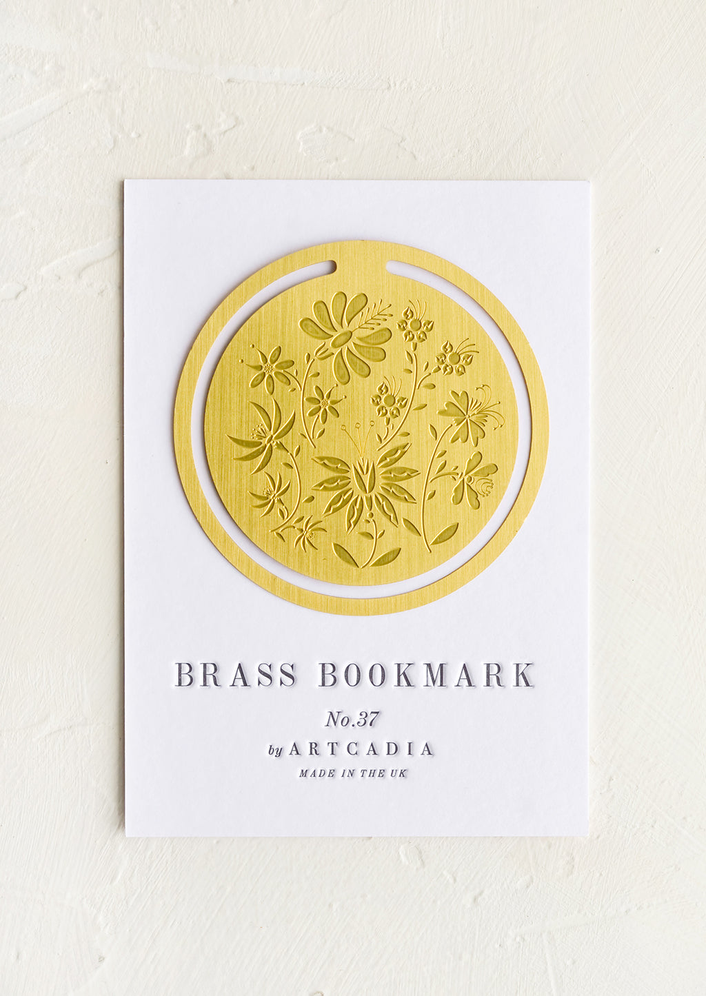 Botanical: A circular brass bookmark with etched botanical pattern.