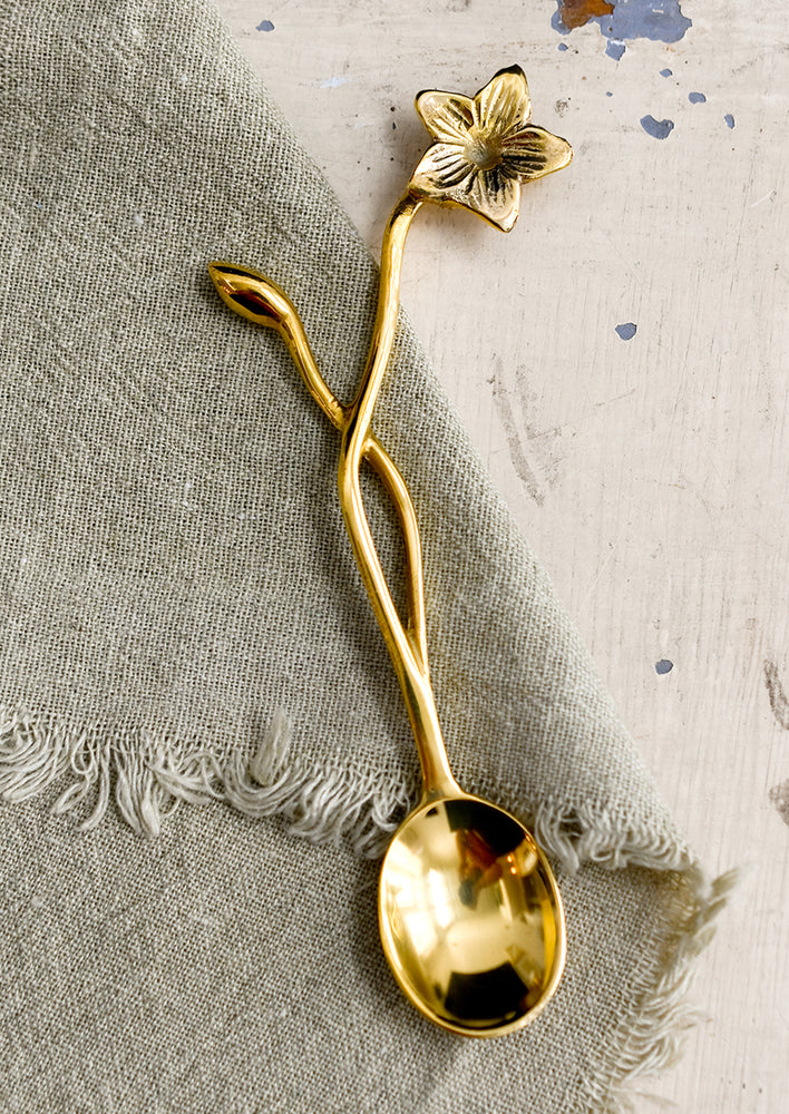 A brass spoon with freeform flower and stem handle.