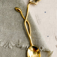1: A brass spoon with freeform flower and stem handle.