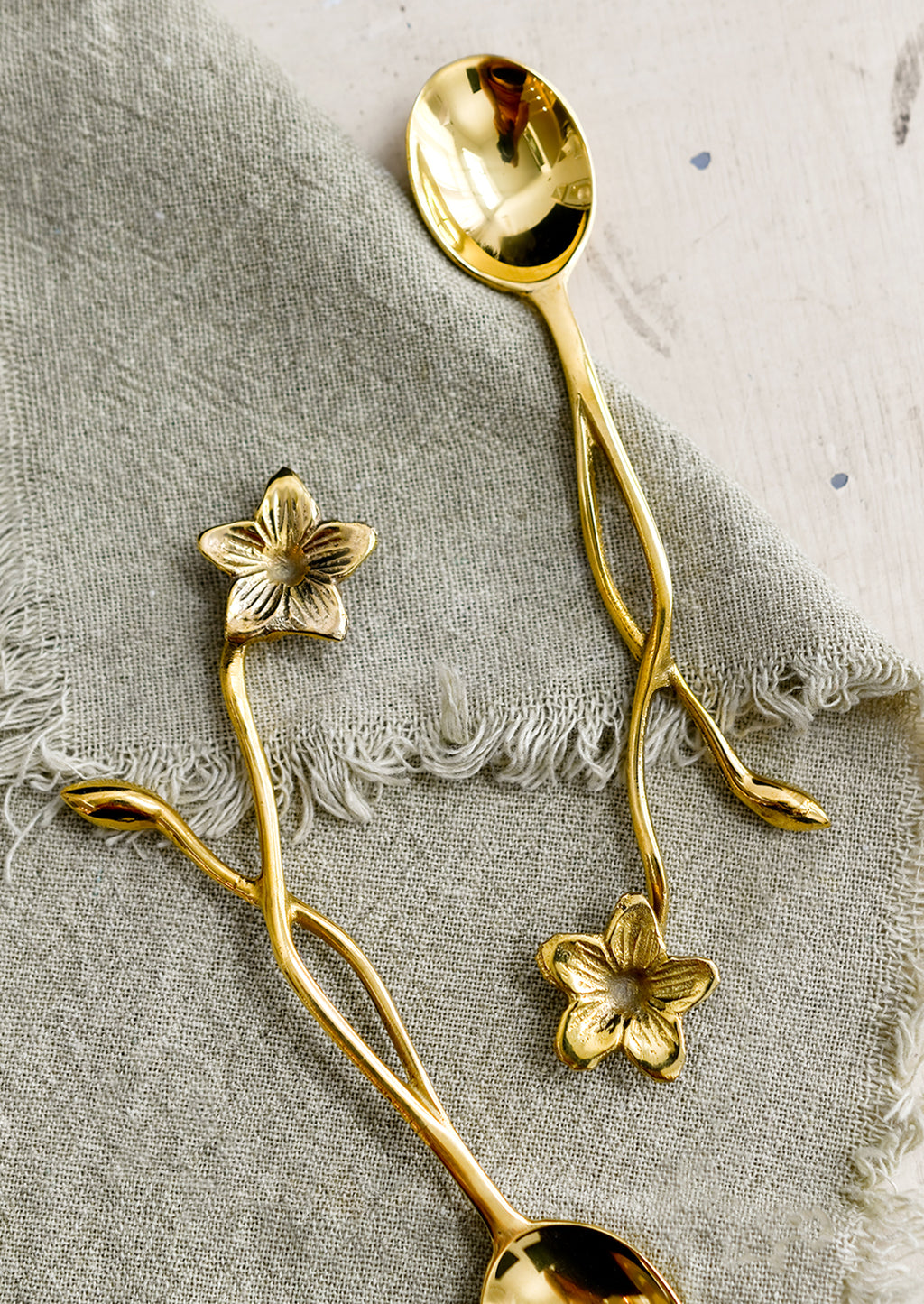 2: A brass spoon with freeform flower and stem handle.