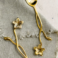 2: A brass spoon with freeform flower and stem handle.