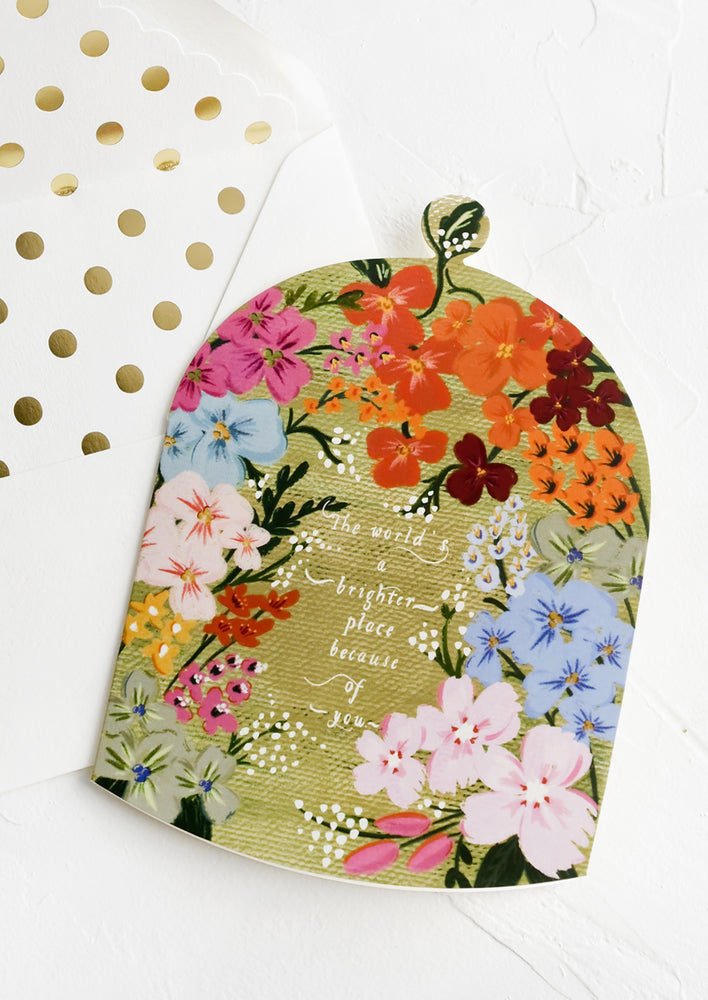 A greeting card in shape of cloche reading "the world's a brighter place because of you".