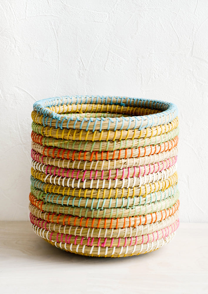Woven seagrass storage basket with colored stripes comprised of woven plastic strips