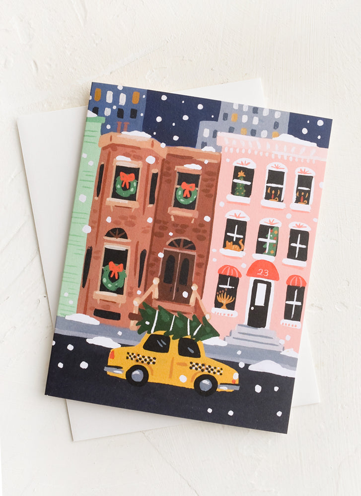 1: A greeting card with illustration of brownstone and taxi with Christmas tree.