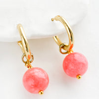 1: A pair of gold hoop earrings with pink spherical stones.