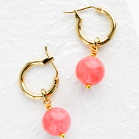 2: A pair of gold hoop earrings with pink spherical stones.