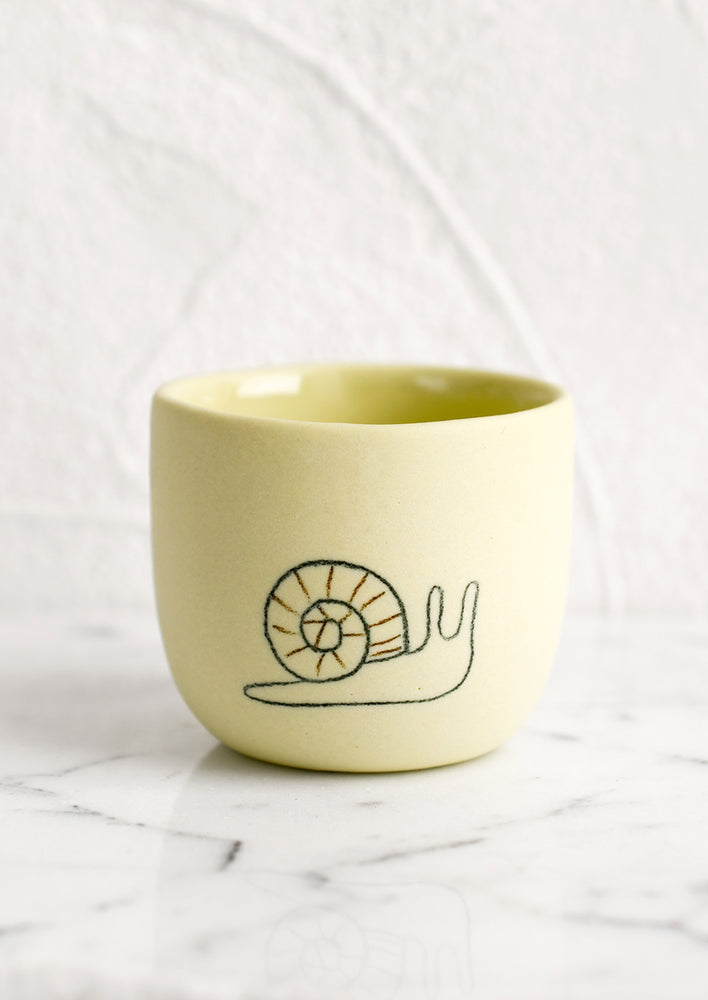 Extra Small / Snail / Maize: An extra small yellow porcelain cup with snail sketch.