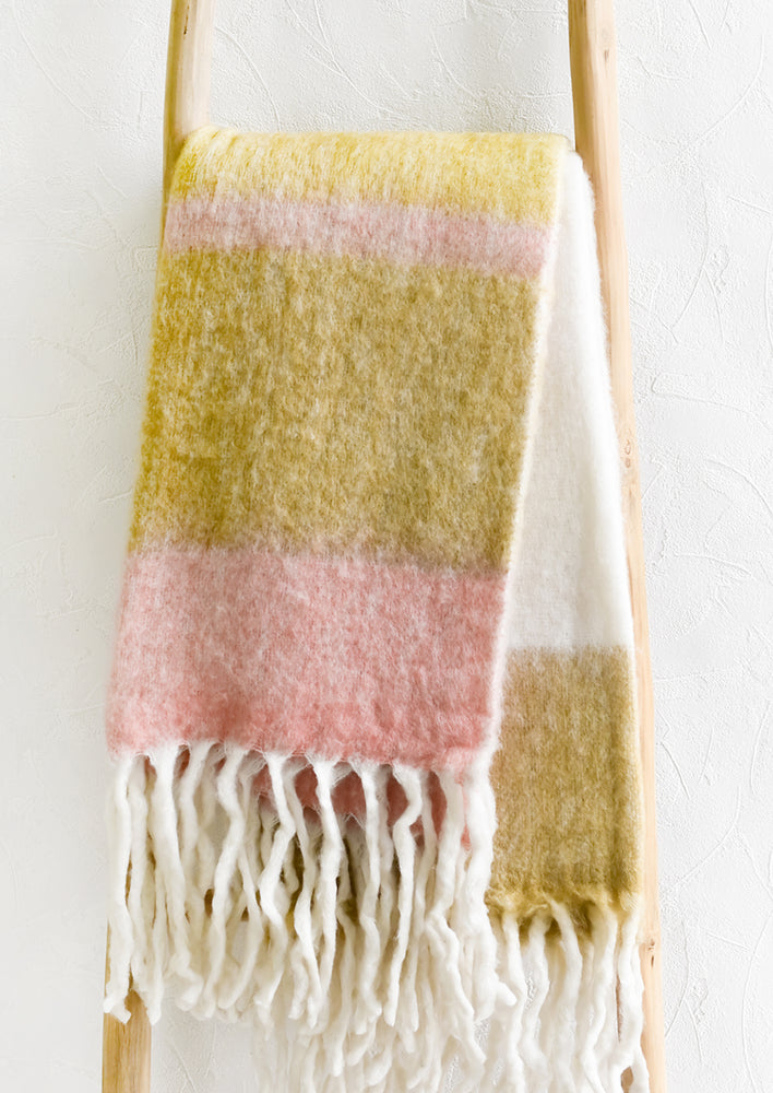 A striped mohair throw blanket in tones of yellow and pink.
