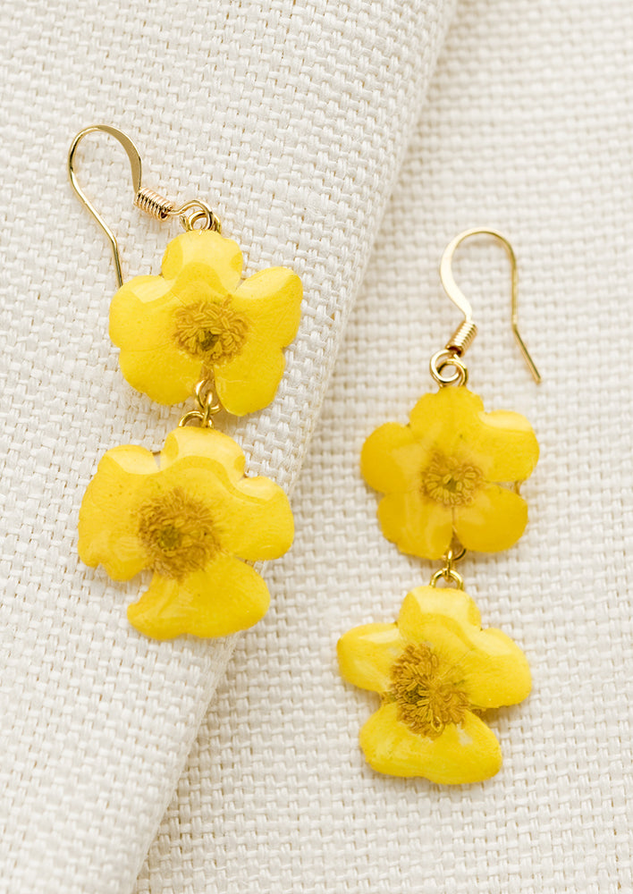 A pair of earrings made from dried buttercup flowers.