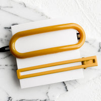 Mustard: A pair of hair clips in oval and rectangular shapes in mustard.