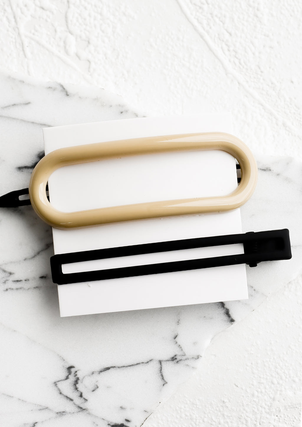 Neutral Multi: A pair of hair clips in oval and rectangular shapes in ivory and black.