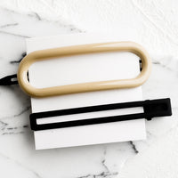 Neutral Multi: A pair of hair clips in oval and rectangular shapes in ivory and black.