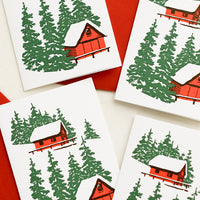 1: A set of letterpress mini enclosure cards with cabin in the woods print and red envelopes.