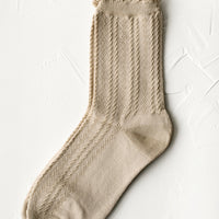 Tan: A pair of cable knit socks with ruffled ankle in tan.