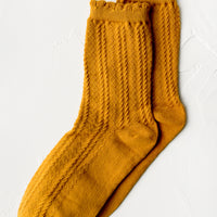 Amber: A pair of cable knit socks with ruffled ankle in amber.