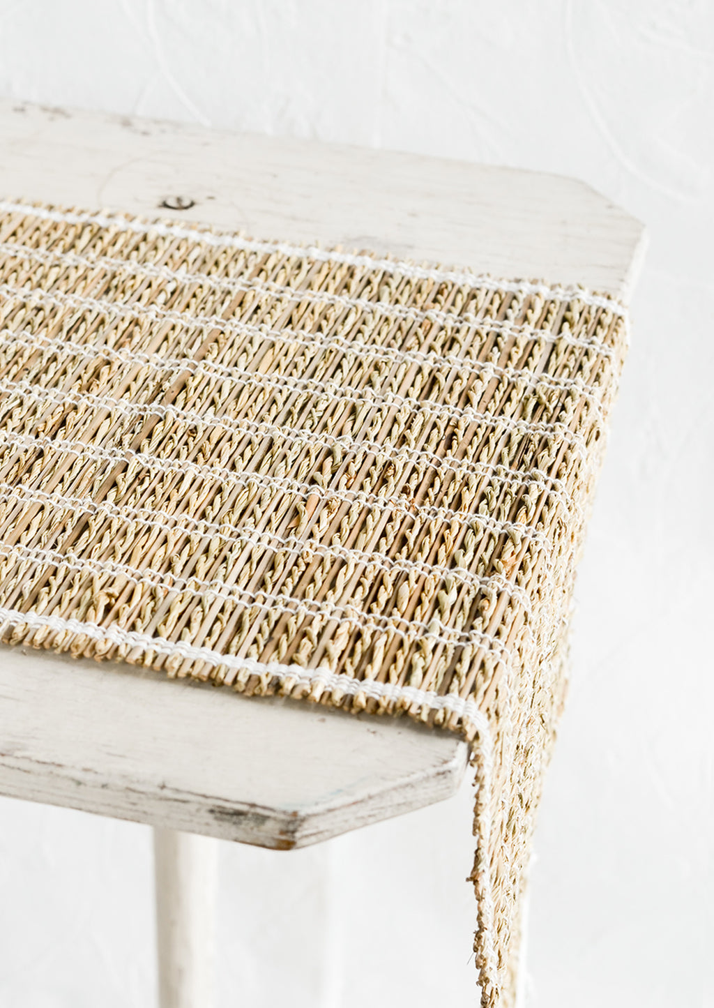 1: A table runner made of natural banana fiber with white stitching.