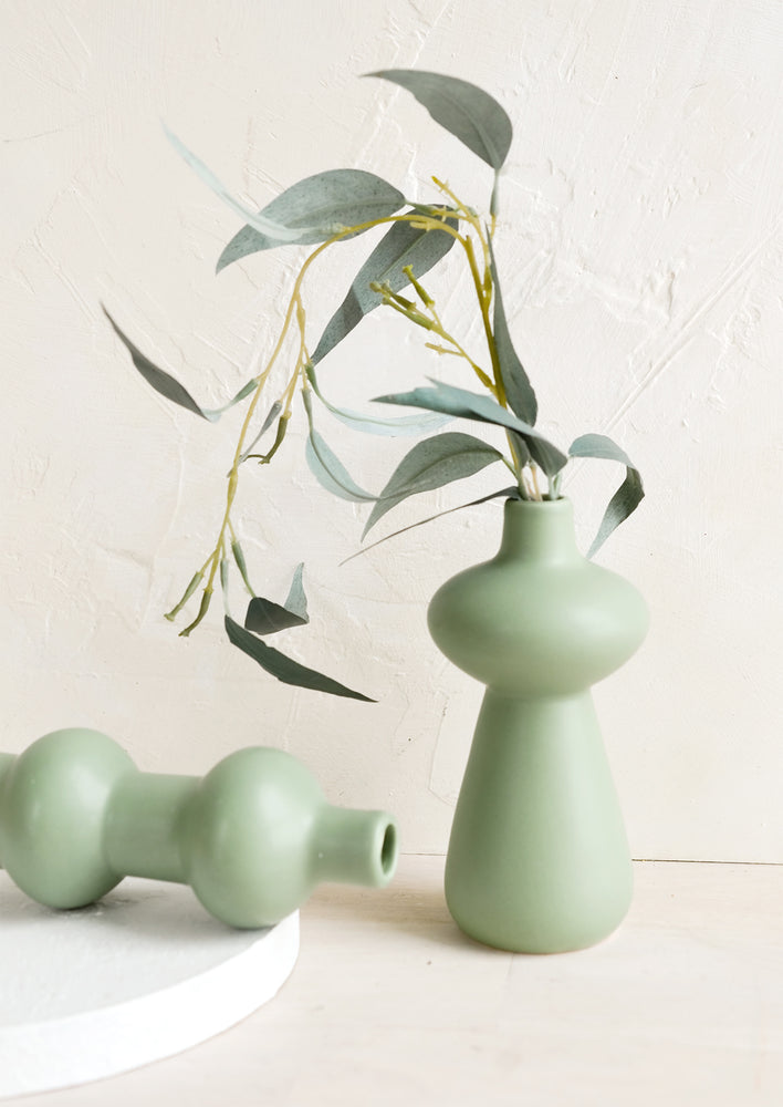 Mint green ceramic bud vases in curvy silhouettes.