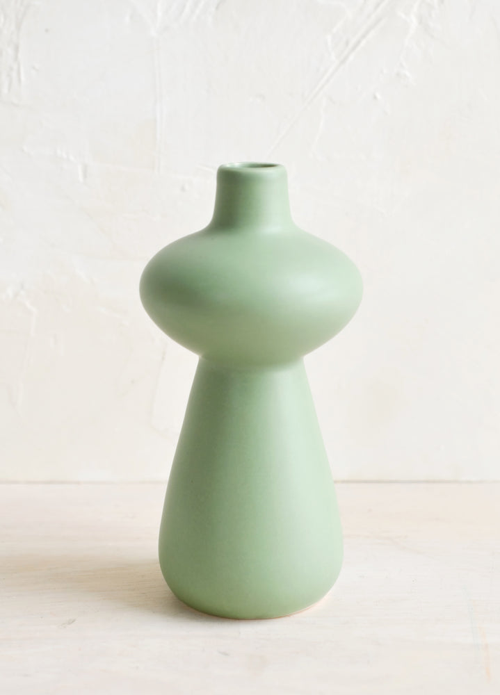 A mint green ceramic bud vase in curvy hourglass silhouette.