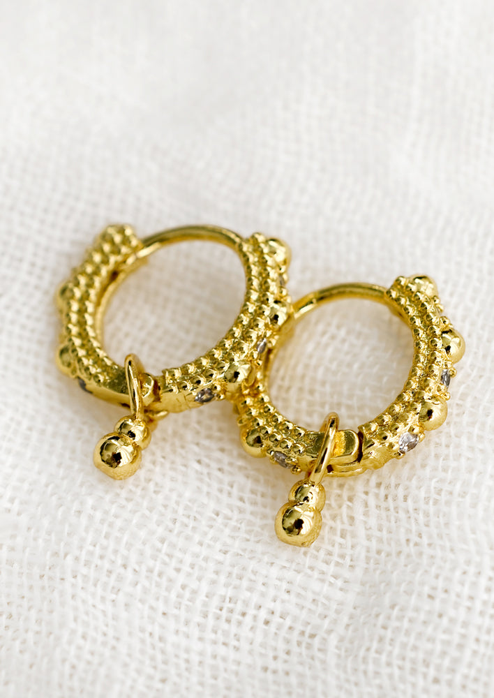 A pair of textured gold hoop earrings with crystal detailing.