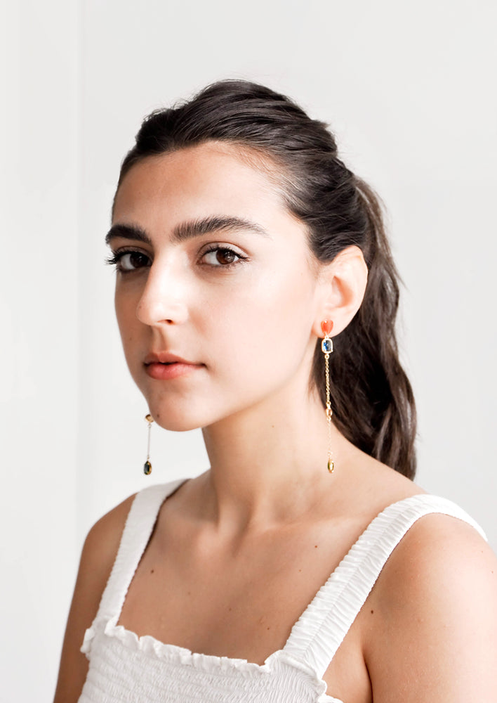 Model wears drop earrings and white tank top.
