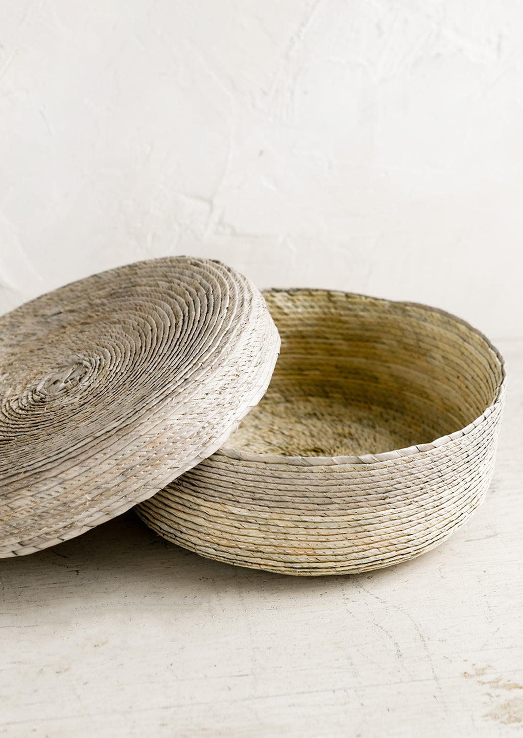 Sea Fog: A shallow, round storage basket with lid, woven from dried palm leaf in two-tone design.