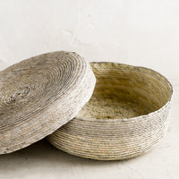Sea Fog: A shallow, round storage basket with lid, woven from dried palm leaf in two-tone design.