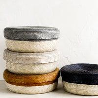 1: Shallow, round palm leaf storage baskets stacked in different colors.