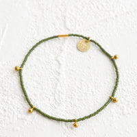 Olive: Bracelet made from olive colored glass seed beads with brass ball accent charms and logo tag