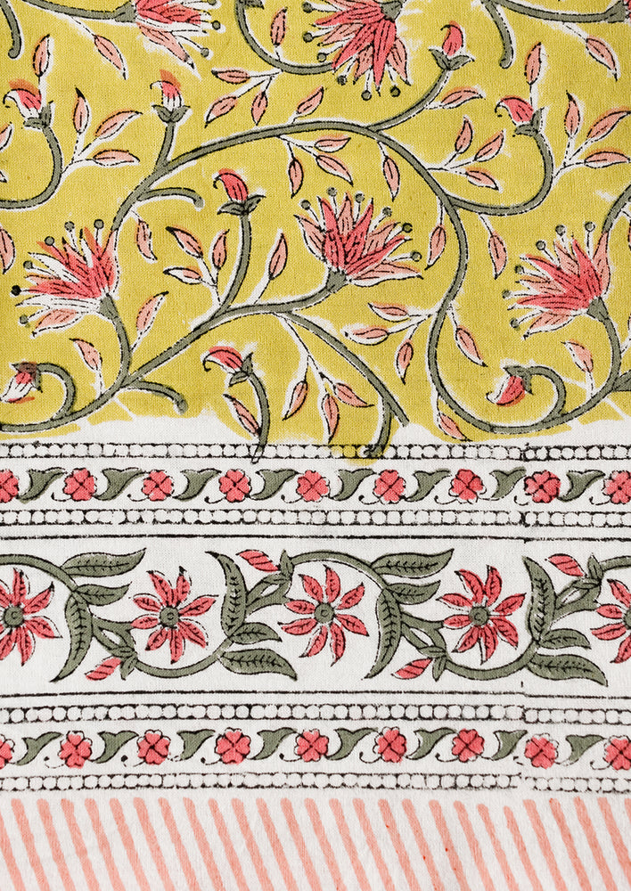 A block printed tablecloth in yellow, pink and green floral.