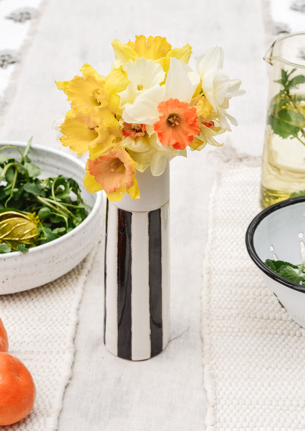 2: A black and white vase on a table with daffodils.